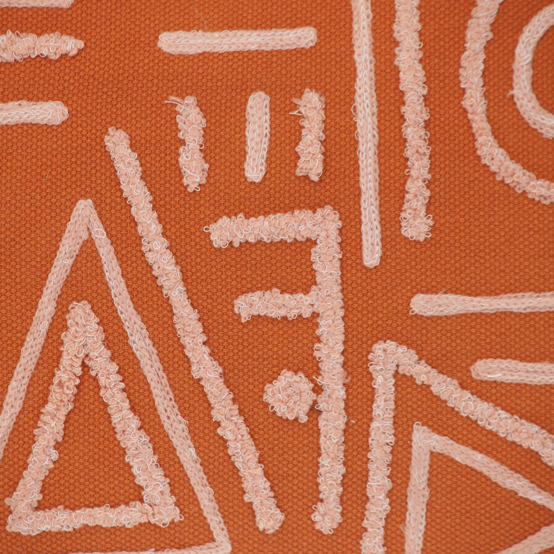Close-up of orange pillow fabric with raised white geometric stitched pattern