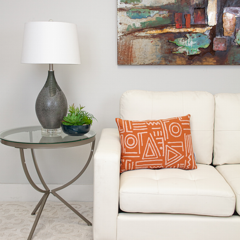 Orange geometric accent pillow with white line pattern on a rectangular cover