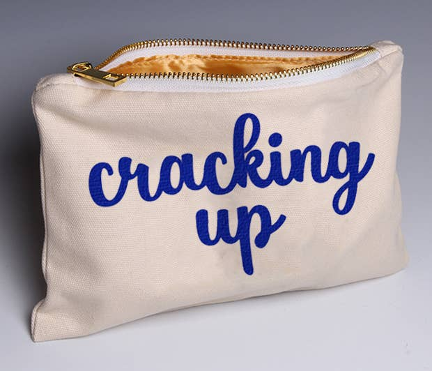 Cream canvas zip pouch with blue 'cracking up' text and gold zipper