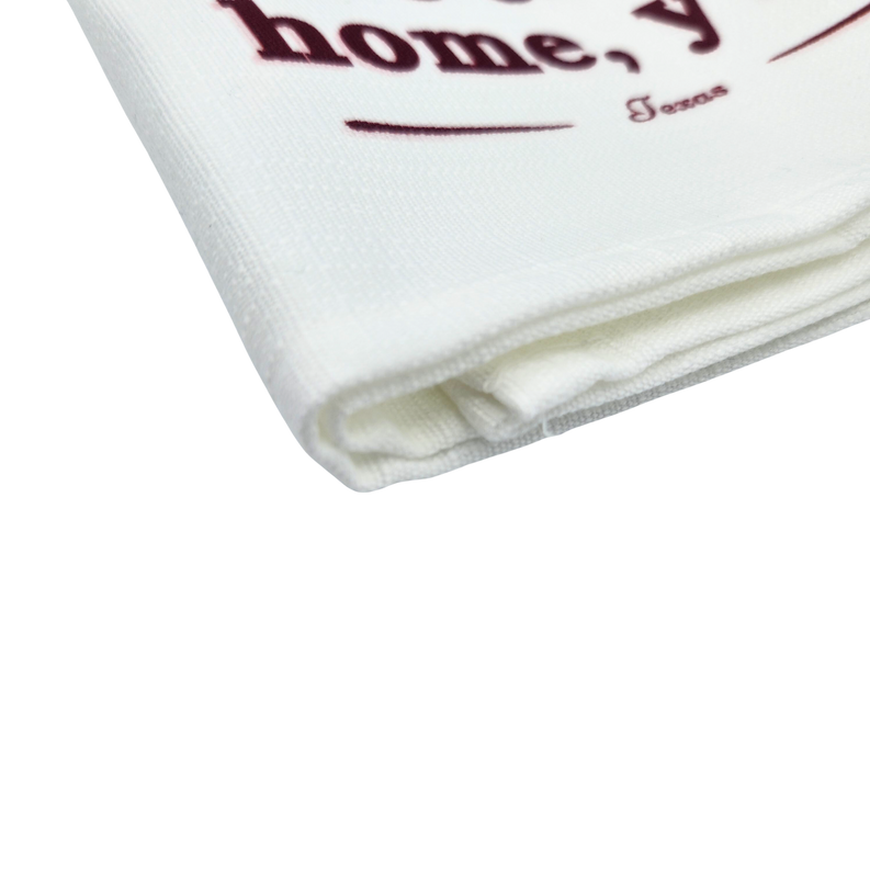White kitchen towel folded edge with textured weave and partial “home” text print