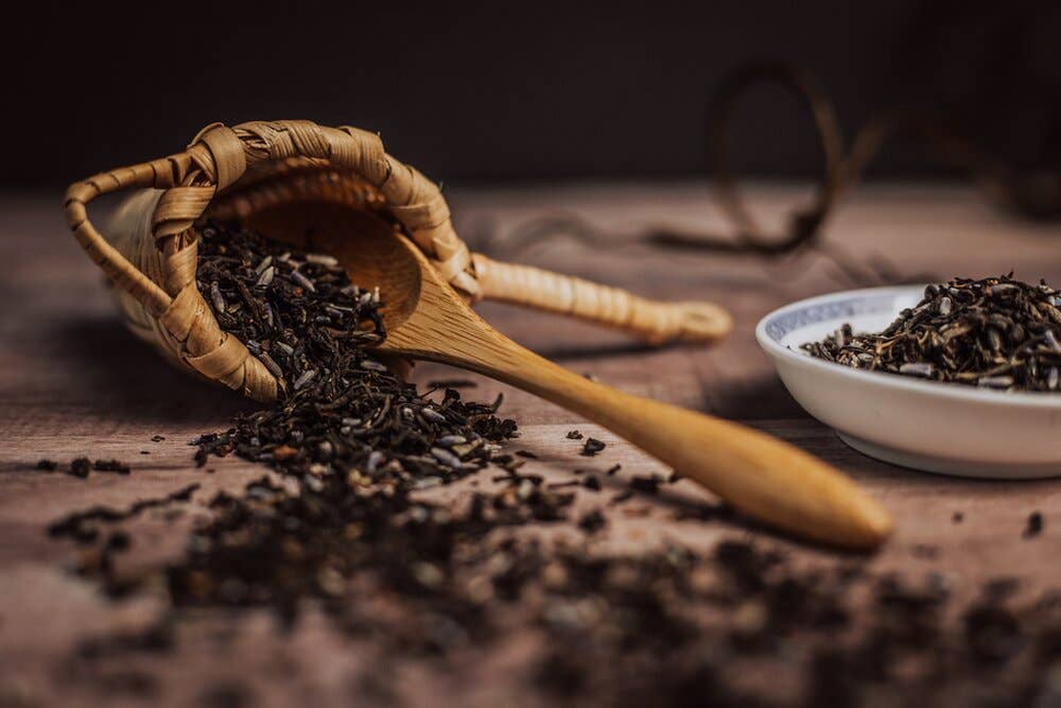 Wooden scoop and basket of dark dried lavender herb leaves with small bowl