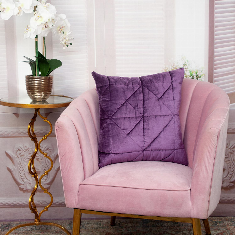 Purple quilted throw pillow on a pink upholstered armchair