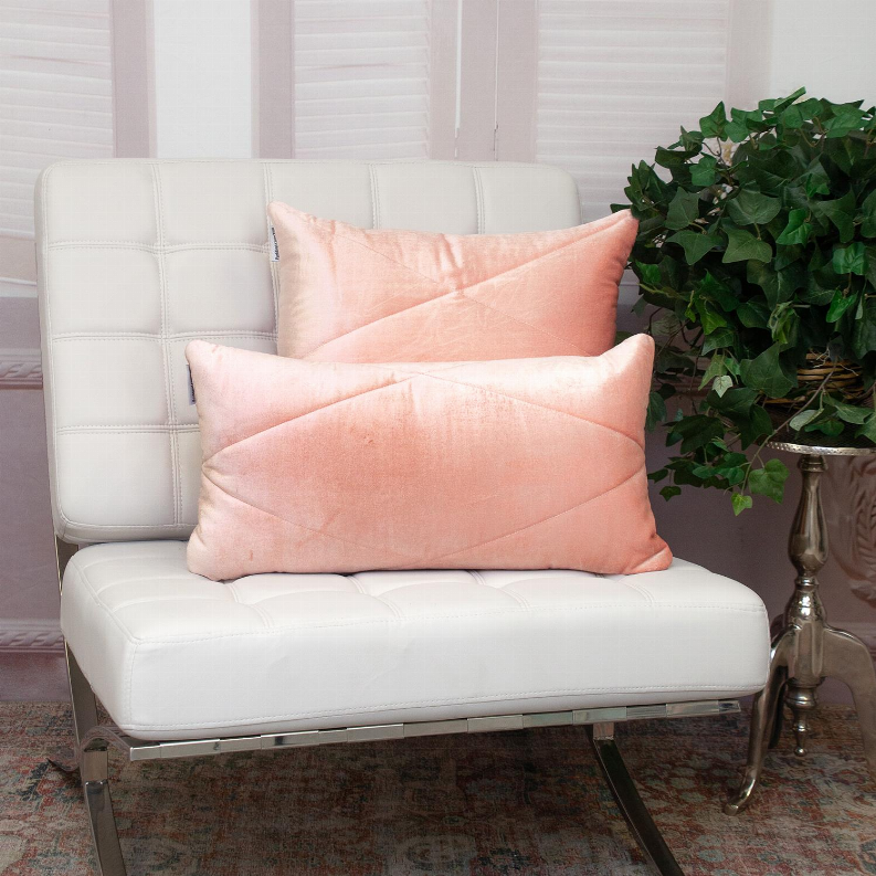 Two light pink quilted throw pillows stacked on a cushioned seat