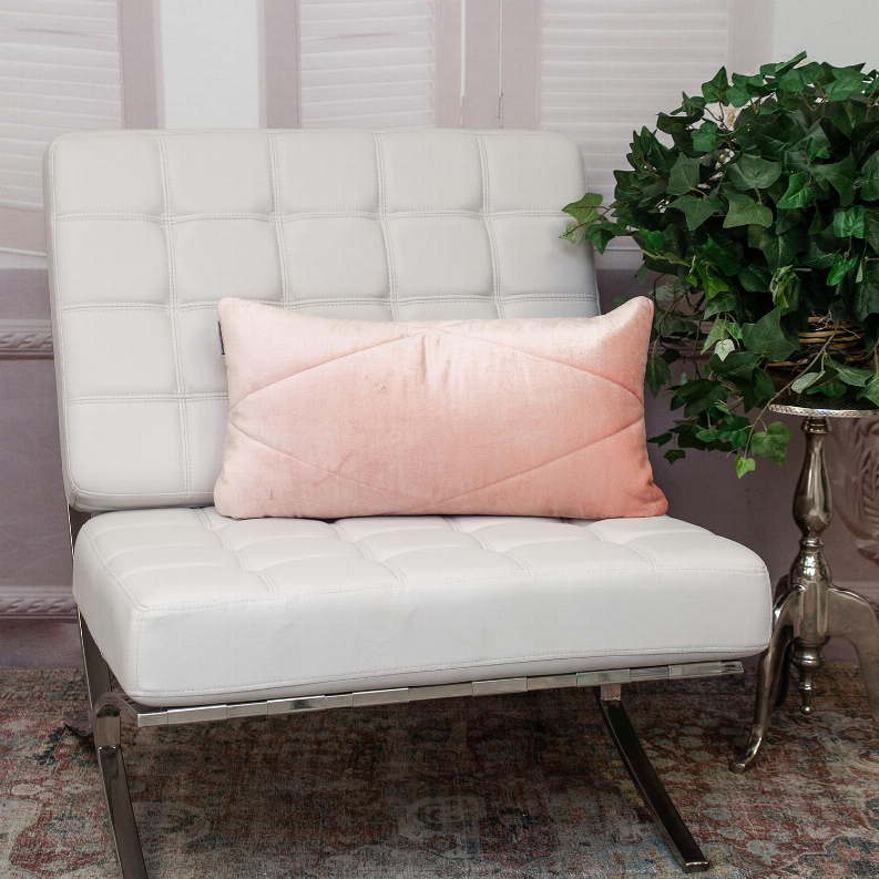 Light pink rectangular quilted pillow on a cushioned seating surface