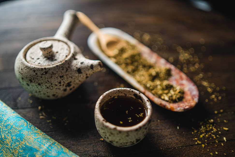 Speckled mate tea set: ceramic cups, gourd with straw, and herbs on spoon