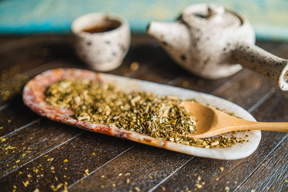 Speckled ceramic mate cups with wooden spoon of green yerba herbs