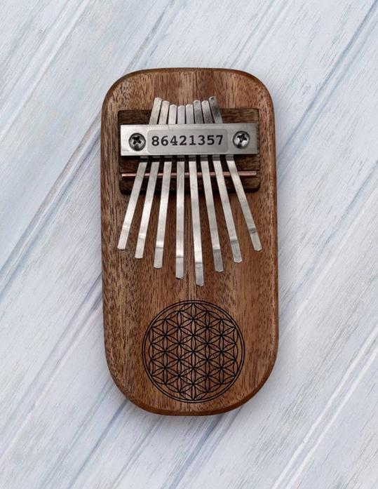 Wooden thumb piano kalimba with metal tines and Flower of Life engraving on front