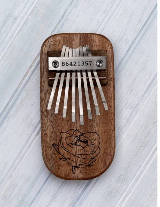 Brown rose-engraved wooden thumb piano with metal tines and numbered label
