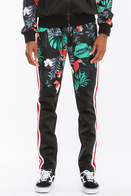 Black tropical print track pants with teal leaves, red stripe detail down the sides