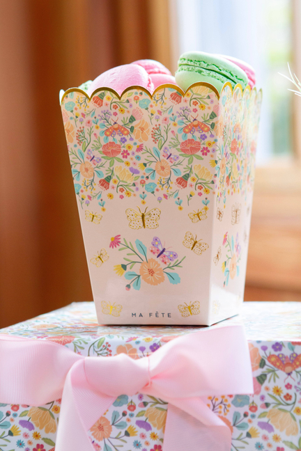 Floral paper treat holder with scalloped top and pink bow, side view