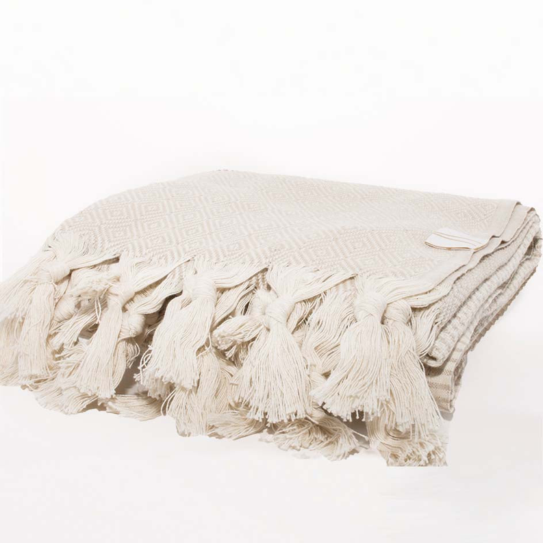 MEDI cream towel with diamond pattern and long tassel fringe on folded towel