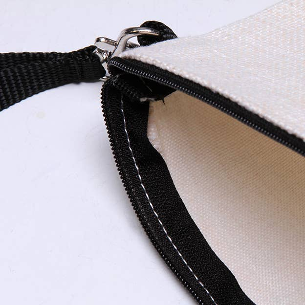 Beige pouch close-up: black zipper, stitched trim, black wrist strap