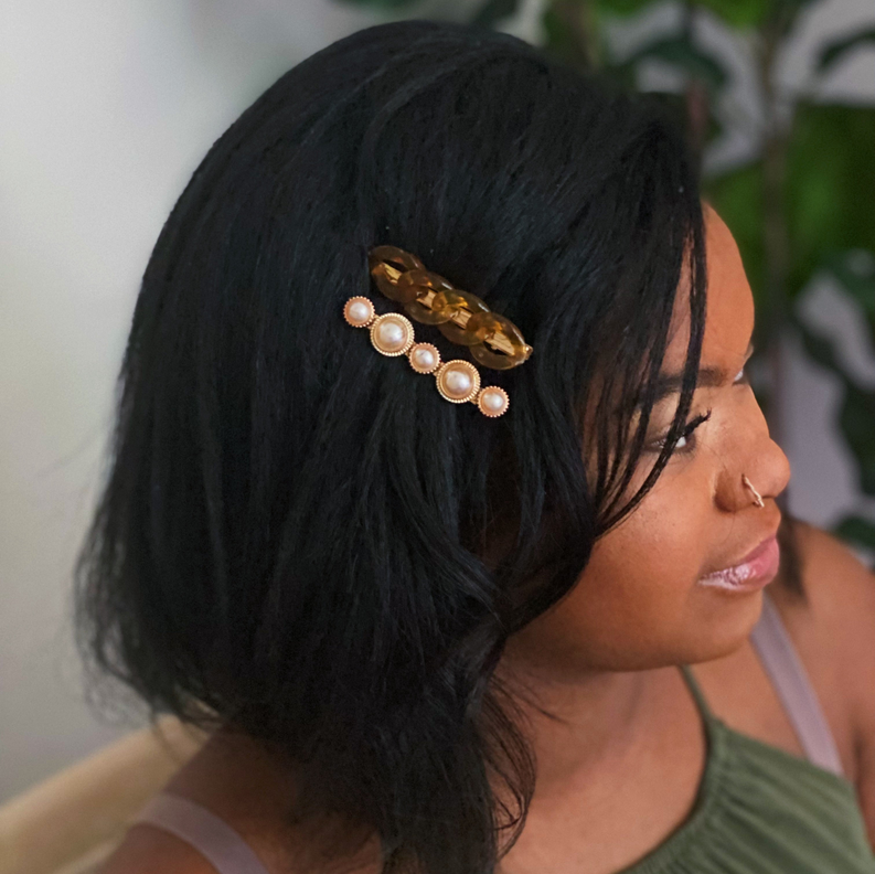 Gold-tone marble chain and pearl hair clip on dark hair