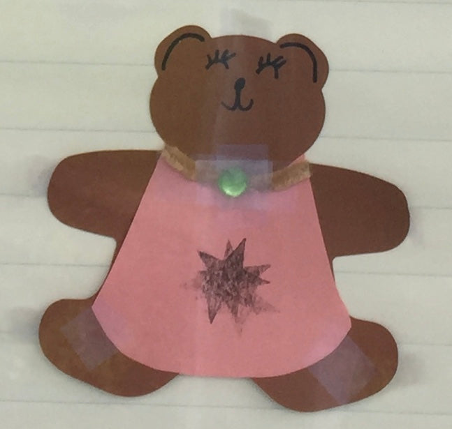Teddy bear foam cut-out in pink dress with black starburst and green glow
