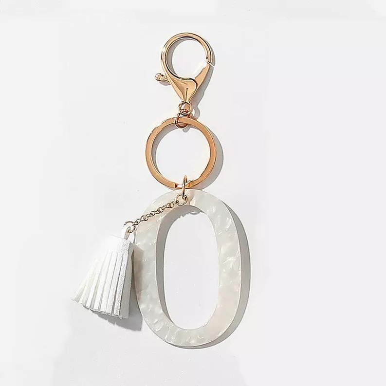 White tassel key chain with gold O-shaped initial ring and split metal clasp