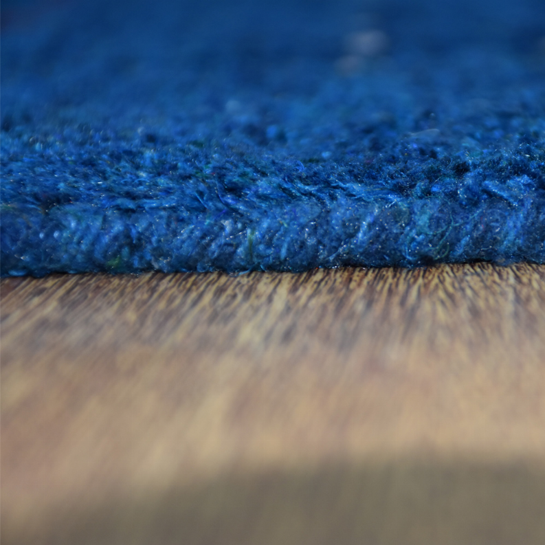 Blue area rug with visible pile edge and thick, tufted construction at border