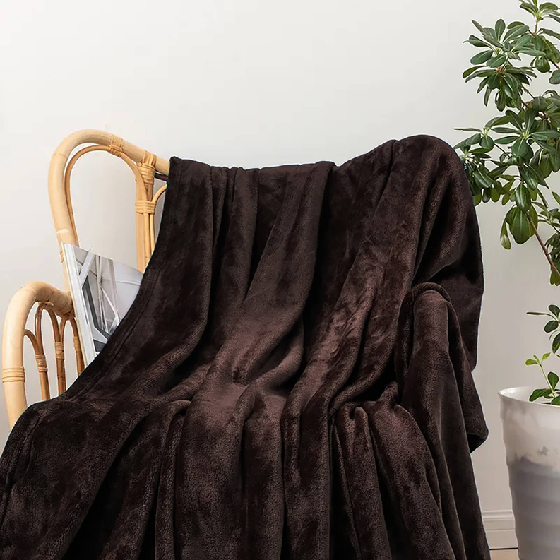 Brown flannel throw blanket draped over wicker chair with gathered folds