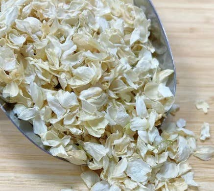 Dried jasmine flowers and petals, pale cream/off-white in a metal bowl