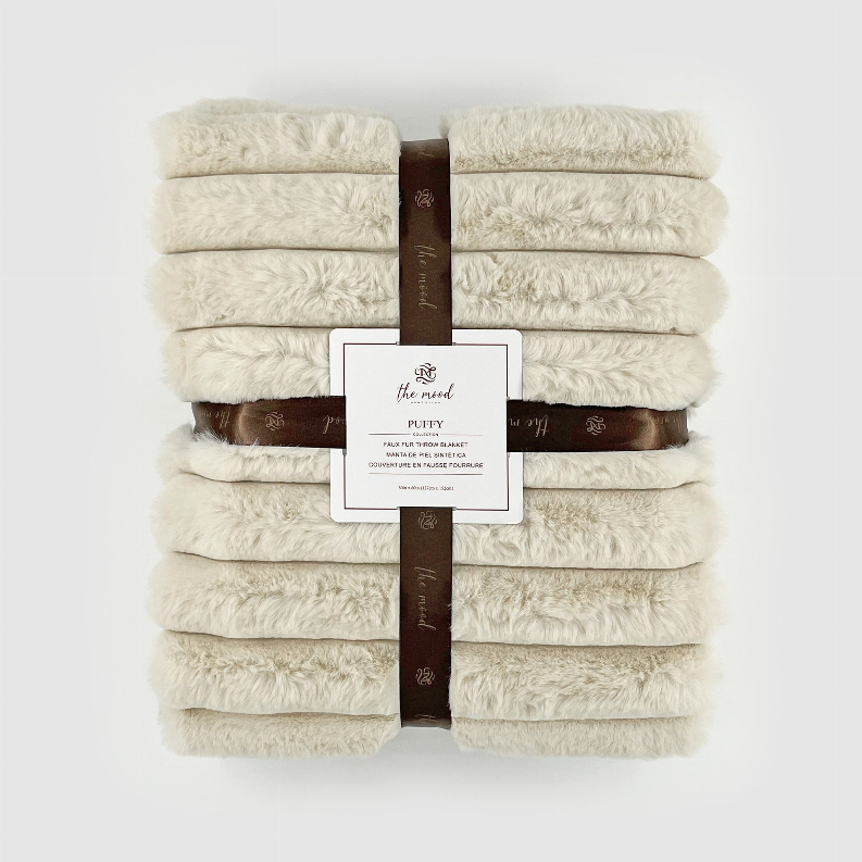 Ivory faux fur throw stack with fabric band and product label on top