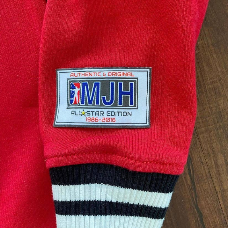 Red sweatshirt sleeve cuff with MJH tag and black-and-white striped rib trim