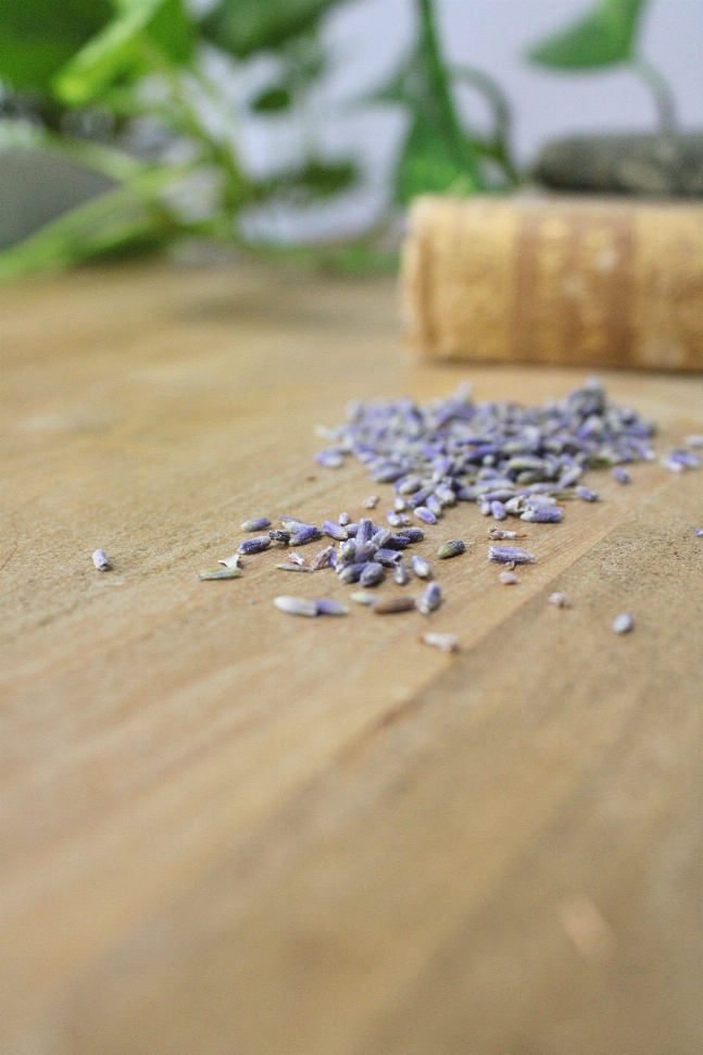 Lavender sugar scrub crystals and dried lavender buds on a wooden surface