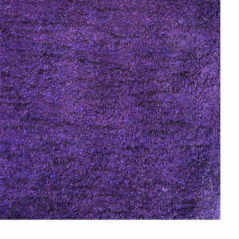 Close-up of hand-knotted silk rug pile in solid dark purple