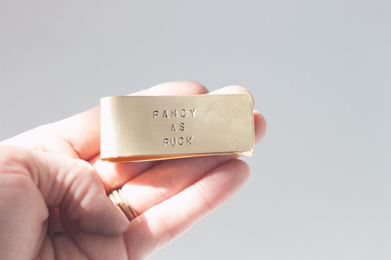 Copper money clip held in hand, engraved "FANCY AS FUCK" front