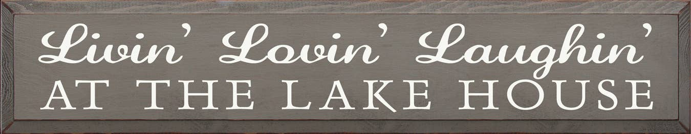 Wood sign with white cursive text: “Livin’ Lovin’ Laughin” and “AT THE LAKE HOUSE”.