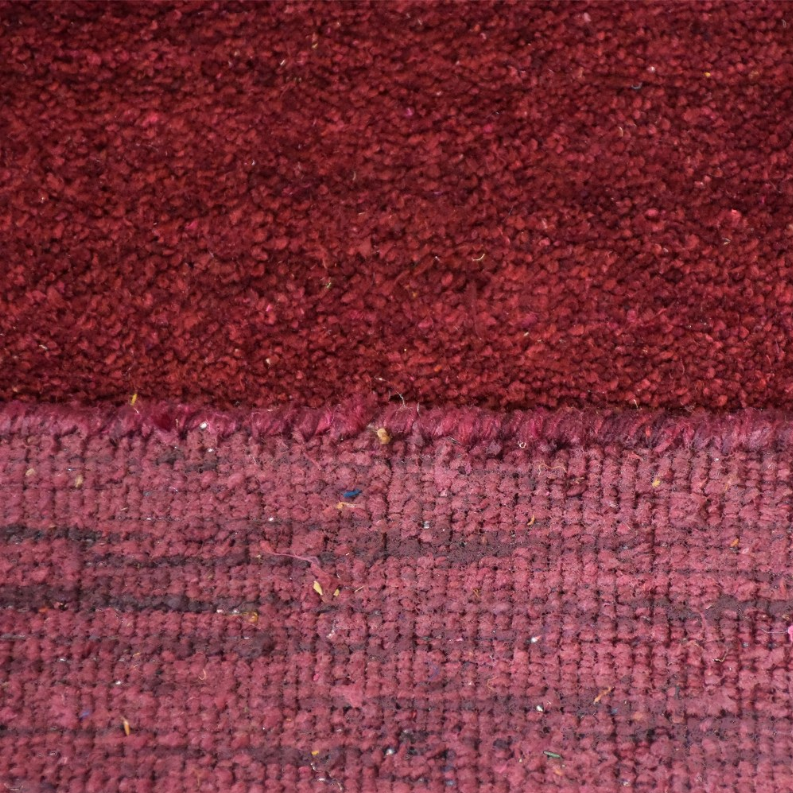 Burgundy rug close-up of dense high pile and woven border edge.