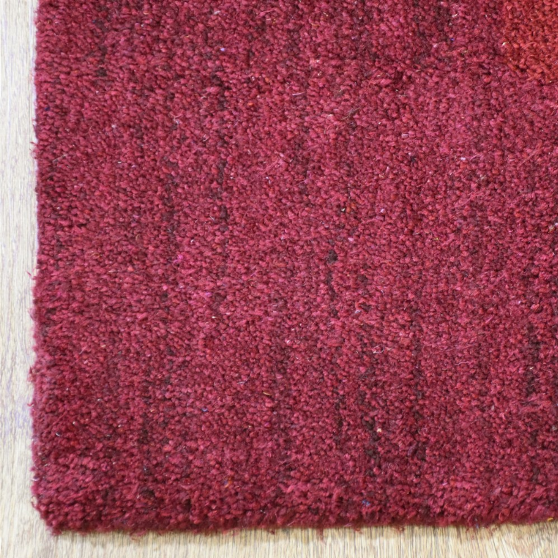 Burgundy rug close-up of dense high-pile texture and cut fiber tips.