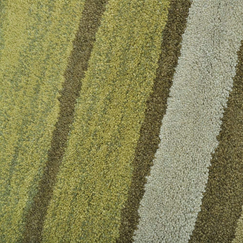 Rug pile close-up with lime, sage, and light gray looped fibers in striped pattern.