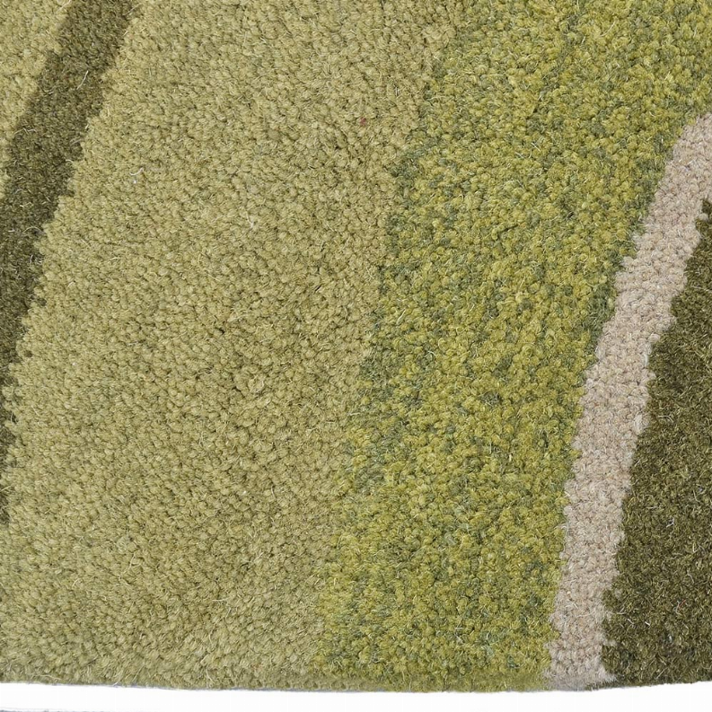 Close-up of round rug texture in olive and sage green with light cream border bands