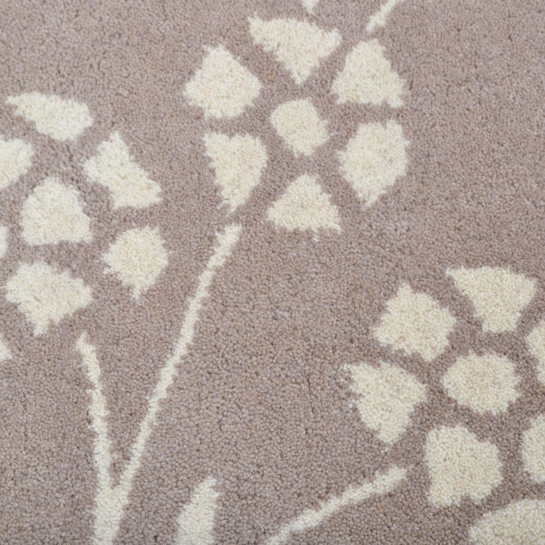 Taupe rug texture with white floral rosette and vine pattern, close-up