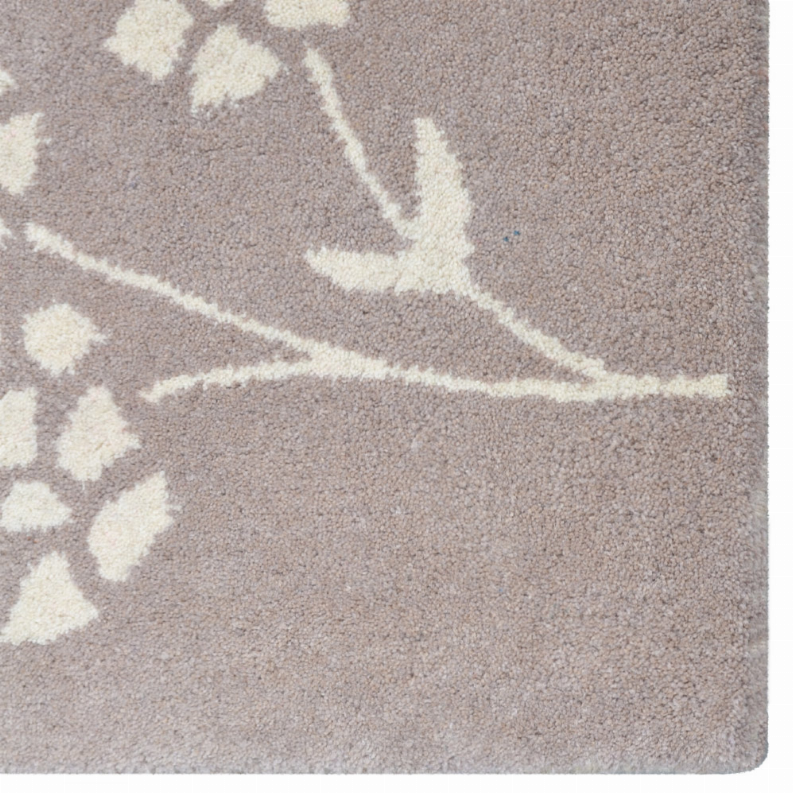 Taupe rug pile with white floral pattern and vine line detail, close-up