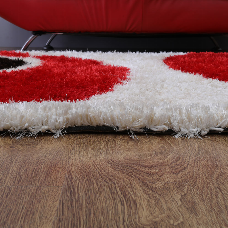 Shag rug edge with thick white pile and red section on hardwood floor