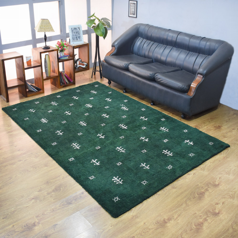 Green area rug with white cross-stitch motifs, flatweave style, in a living room scene