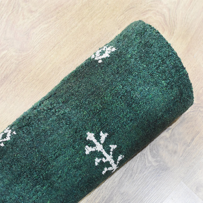 Green rug corner with white snowflake-style motif on textured surface