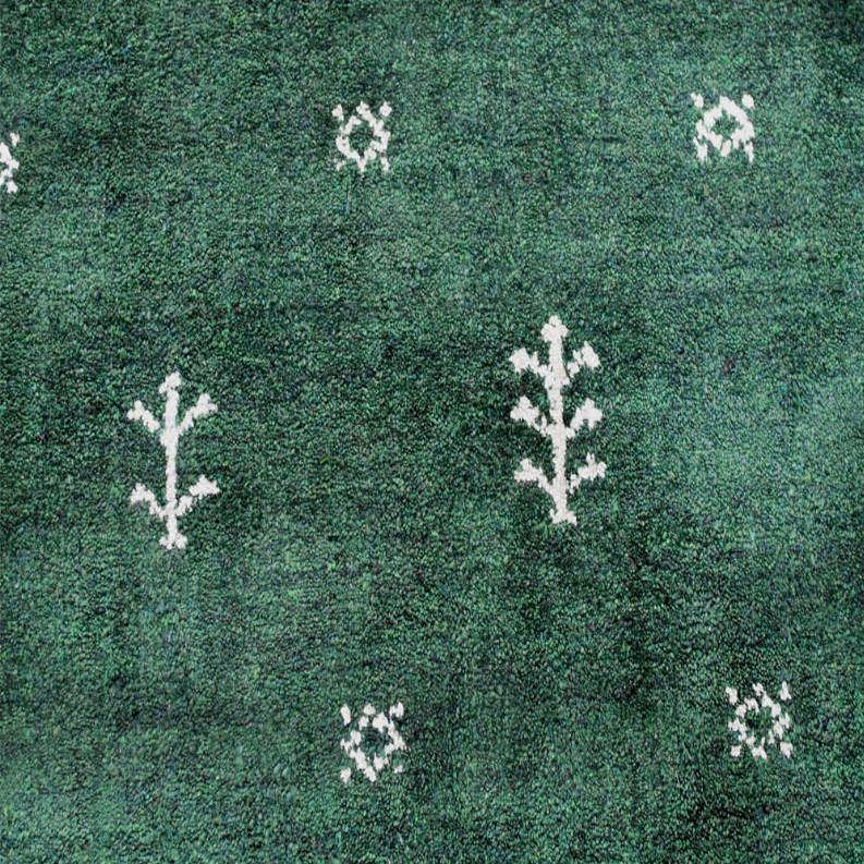 Close-up of green rug texture with white branch-like motifs