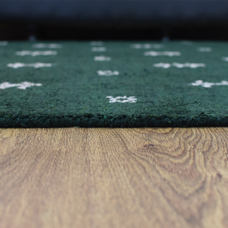 Green rug close-up showing dense textured pile and white motif detail