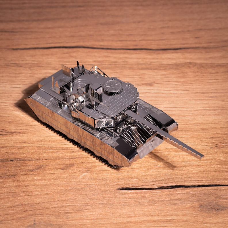 Metal tank model on wooden surface, side view with turret, tracks, gray and black