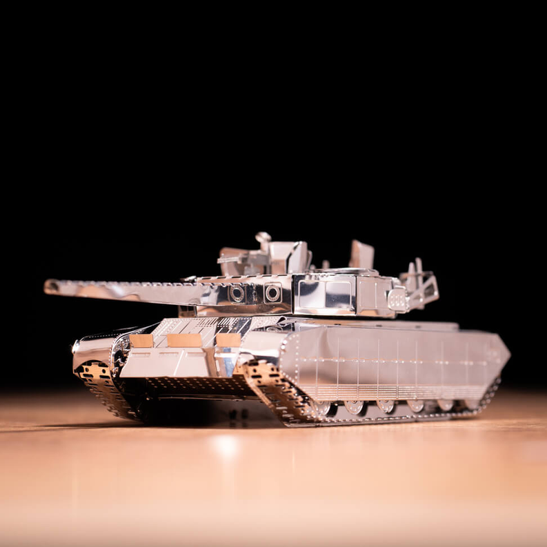 Metal tank model close-up on reflective base, turret and barrel, gray and silver