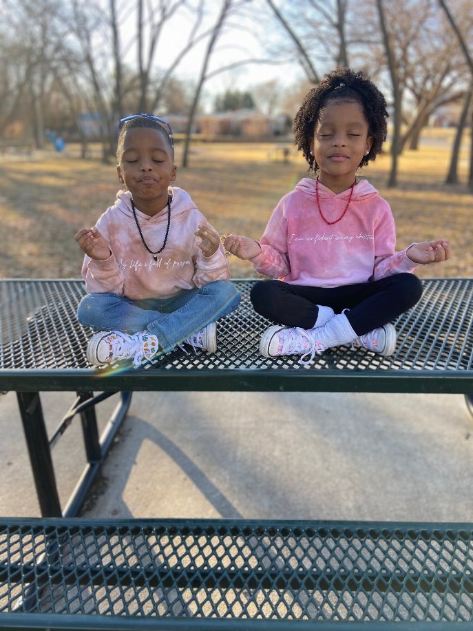 Kids wearing light pink plant-dyed hoodies with white script affirmation on front