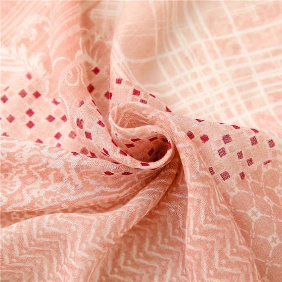 Peach-pink sheer voile scarf, tightly wrapped showing repeating geometric motifs