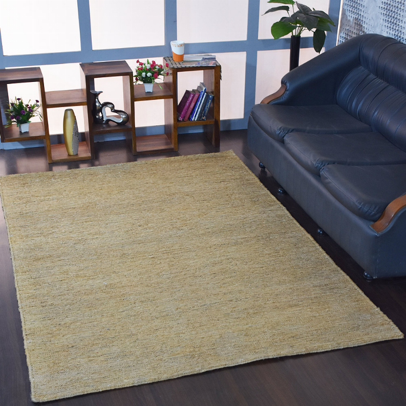 Solid jute area rug in light beige placed on dark wood floor beside blue sofa