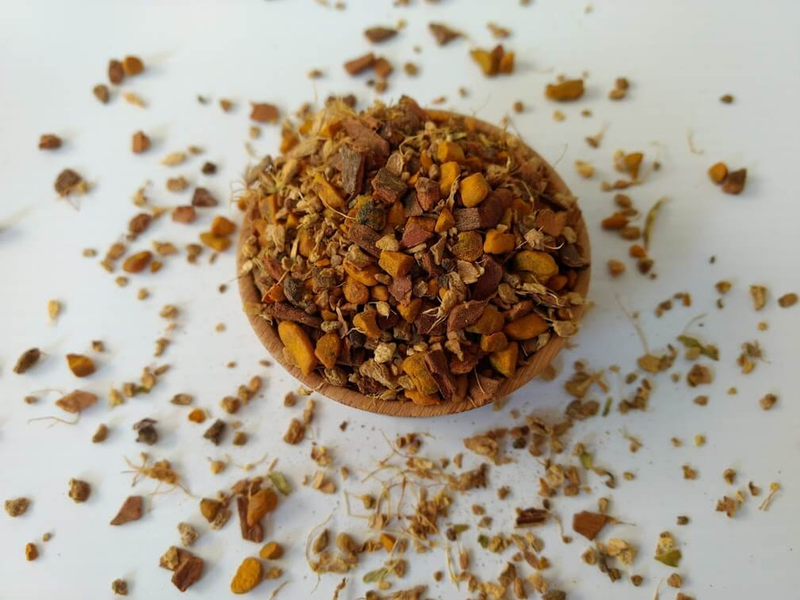 Herbal turmeric chai spice blend bowl with scattered dried herb and spice pieces