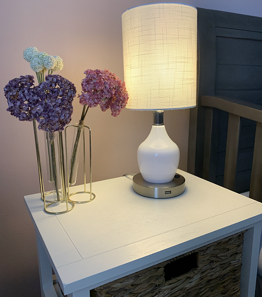 White fabric-shade Angel-Gen 2 lamp with glowing bulb on a side table