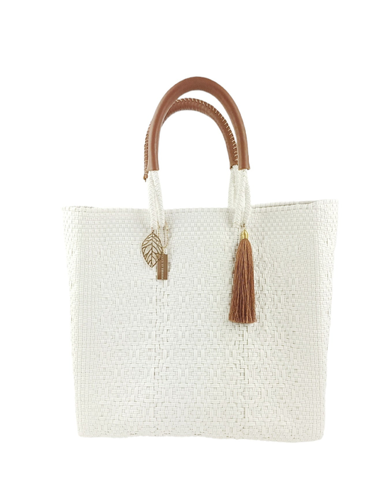 White woven tote bag with brown curved handles and leaf plus tassel charms