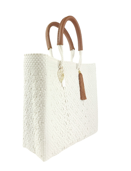 White woven tote bag, 3/4 view, with brown handles and tassel plus leaf charm