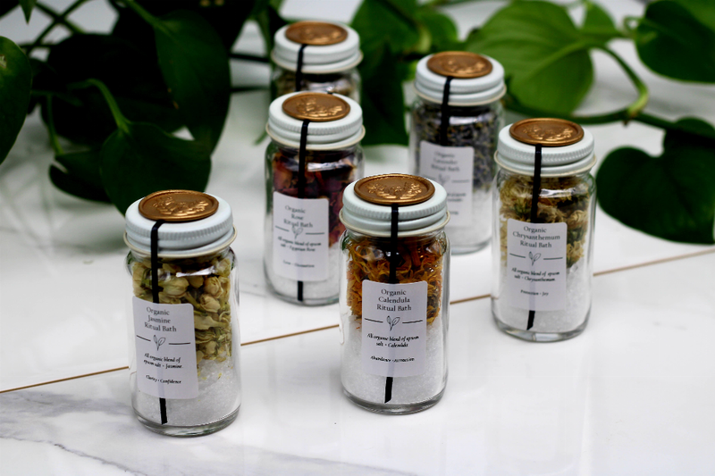 Cluster of assorted bath salt jars in clear glass with gold lids and printed front labels.