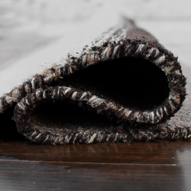 Hand-knotted area rug rolled edge detail, dark pile with light speckled loops